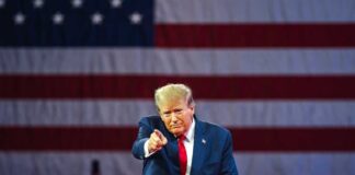 Man points in front of American flag backdrop.